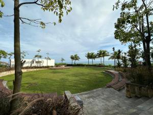 a park with a lawn with palm trees and the ocean at One bedroom apartment at Borneo Bay City in Klandasan Kecil