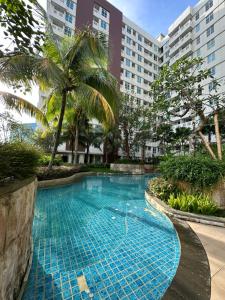 a swimming pool in a resort with palm trees and buildings at One bedroom apartment at Borneo Bay City in Klandasan Kecil