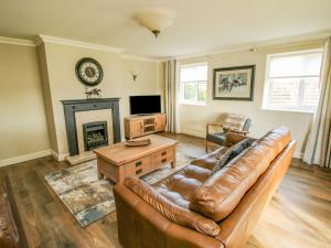 a living room with a leather couch and a fireplace at The Marshes in Welshpool