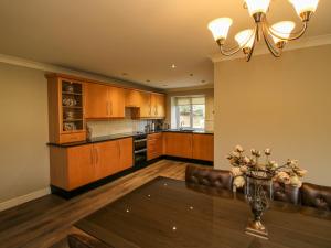 a kitchen with wooden cabinets and a table with a vase of flowers at The Marshes in Welshpool