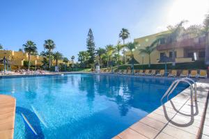 una piscina en un complejo con sillas y palmeras en Apartment in resort, en Corralejo