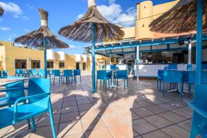 um pátio com mesas azuis, cadeiras e guarda-sóis em Apartment in resort em Corralejo