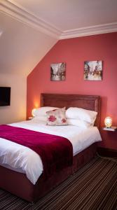 a bedroom with a large bed with a red wall at Kintrae B&B in Buckie