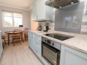 a kitchen with white cabinets and a stove top oven at Salakee in Penzance