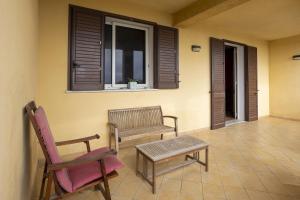 un porche con 2 bancos, una mesa y una silla en Ginevra Vista Mare, en Campobello di Mazara
