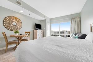 a white bedroom with a large bed and a table at Luau #6633 in Destin