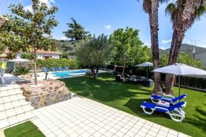 Senmanat的住宿－Catalunya Casas Stunning Villa with private pool 33 km to Barcelona，一个带蓝色椅子和遮阳伞的庭院和一个游泳池