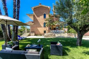 Senmanat的住宿－Catalunya Casas Stunning Villa with private pool 33 km to Barcelona，一座带草坪、椅子和遮阳伞的房子