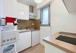 a small kitchen with white cabinets and a window at L'escapade - Centre Ville - Parking - Balcon in Rennes