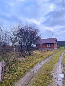 a dirt road next to a red brick house at Domek z ogrzewaniem podłogowym in Wyszki