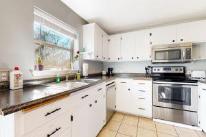 a kitchen with white cabinets and a sink and a microwave at Logan's Hideaway in Eureka Springs