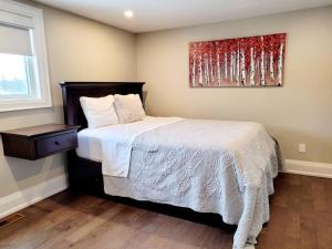 Un dormitorio con una cama y un cuadro en la pared. en Chemong Lake Waterfront Cottage☆privateboatlaunch, en Lakefield
