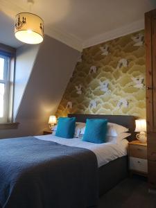 a bedroom with a large bed with blue pillows at Fraoch House in Edinburgh