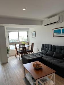 sala de estar con sofá negro y mesa en Apartamento en Ocean Drive Country, en Punta del Este
