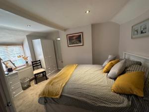 ein Schlafzimmer mit einem großen Bett mit gelben Kissen in der Unterkunft Cottage en-suite room with private lounge in Bridport