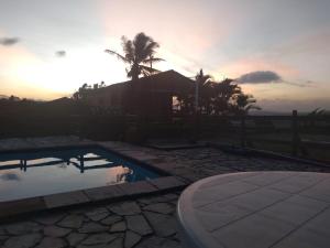 una casa con una piscina y una palmera y la puesta de sol en Casa Aconchegante na Serra de Gravatá, en Gravatá