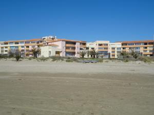 a building on the beach next to a sandy beach at SAVANNA BEACH I Joli T2 piscine vue mer Cap d'Agde in Cap d'Agde