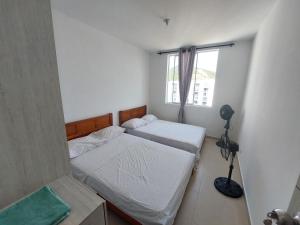 - 2 lits dans une petite chambre avec fenêtre dans l'établissement Apartamento Aqualina Orange Decimo Piso 2 Habitaciones Vista a Montañas, à Girardot