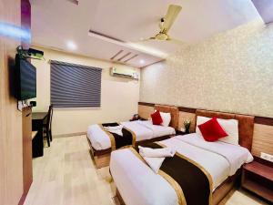 a room with three beds and a tv at HOTEL SM DECCAN PARK in Shamshabad