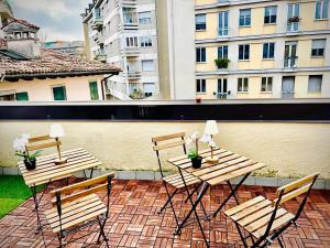 three wooden tables and chairs on a patio with buildings at Alkecè White in Udine +4 photos