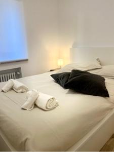 ein weißes Bett mit Handtüchern und Kissen darauf in der Unterkunft Alkecè White in Udine