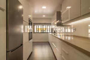 a large kitchen with white cabinets and a stainless steel refrigerator at Modern 3 BDR Apartment by LovelyStay in Ramada