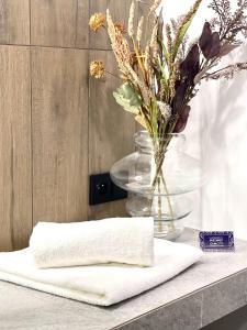 a white towel on a counter with a vase of flowers at ApartamentCentrum-CHARLOTTE -PARKING- in Bolesławiec