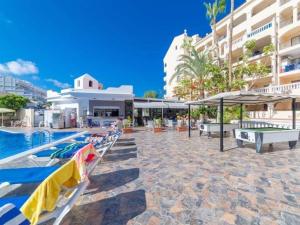 a resort pool with lounge chairs and umbrellas at DORY HOUSE LOS CRISTIANOS in Los Cristianos