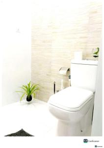 a white bathroom with a toilet and a plant at Ayona Beach Villa in Katuneriya
