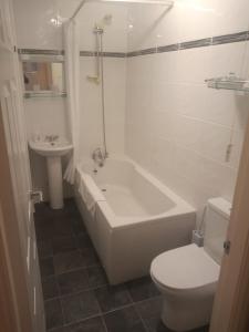 a bathroom with a tub and a toilet and a sink at Wedgwood Guest House in Llandudno