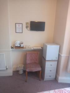 a desk with a computer and a chair in a room at Wedgwood Guest House in Llandudno