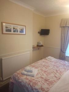 a bedroom with a bed with two towels on it at Wedgwood Guest House in Llandudno