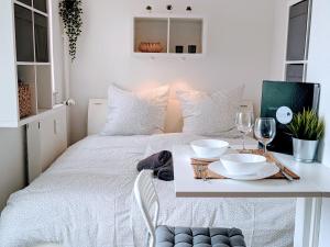 a white bed with a table and wine glasses on it at Tiny Apartment - Innenstadt l Smart TV l Küche in Kaiserslautern