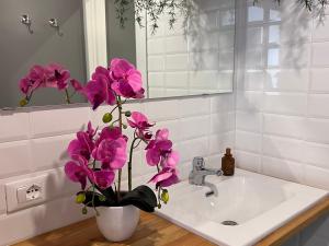 ein Waschbecken mit einer Vase mit lila Blumen in der Unterkunft BRIC NEST il luogo ideale per la tua vacanza. in Florenz