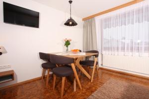 a dining room with a table and chairs and a television at Gästehaus Etschmann in Riezlern