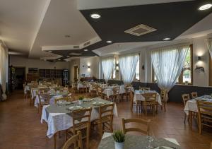 a restaurant with white tables and chairs and white curtains at Santamaria Village Resort Ascea in Ascea