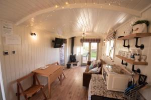 a living room with a couch and a table in a tiny house at Luxury Twin Shepherds Hut - Cosy & Romantic in Llandudno