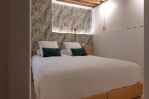 a bedroom with a white bed with two green pillows at MiHotel Georges in Lyon