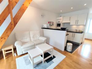 salon z białą kanapą i kuchnią w obiekcie Appartement avec WIFI, parking au centre de PERROS-GUIREC Réf - 953 w mieście Perros-Guirec