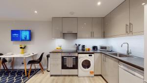 - une cuisine avec des placards blancs et un lave-linge/sèche-linge dans l'établissement Wimbledon Studios, à Londres