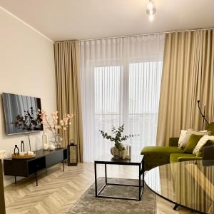 a living room with a green couch and a large window at ApartamentCentrum-CHARLOTTE -PARKING- in Bolesławiec