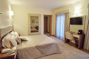 a hotel room with a large bed and a desk at Hotel O Guerreiro in Ponte da Barca