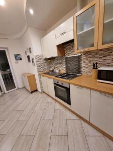 a kitchen with white cabinets and a wooden floor at Appartamento Valentinis 74 in Monfalcone