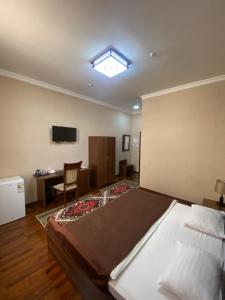 a bedroom with a bed and a desk and a television at Hotel Vardonze in Bukhara