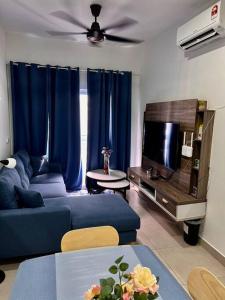 ein Wohnzimmer mit einem blauen Sofa und einem TV in der Unterkunft Dilla Homestay At Bangi UKM Kajang in Kajang