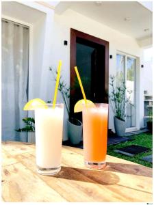duas bebidas sentadas numa mesa de madeira com palhinhas amarelas em Ayona Beach Villa em Katuneriya