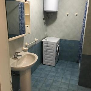 ein Badezimmer mit einem Waschbecken und einer Waschmaschine in der Unterkunft La Rosa Dei Venti in Olbia