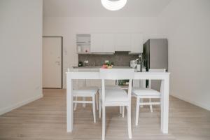 a white kitchen with a white table and chairs at Realkasa La Pigna Flat in Bologna