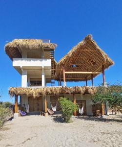 a building with a straw roof on the beach at Casa Gitana in Chamuscadero