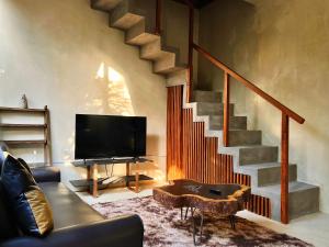 a living room with a television and a staircase at Pacha Tulum Boutique Hotel in Tulum